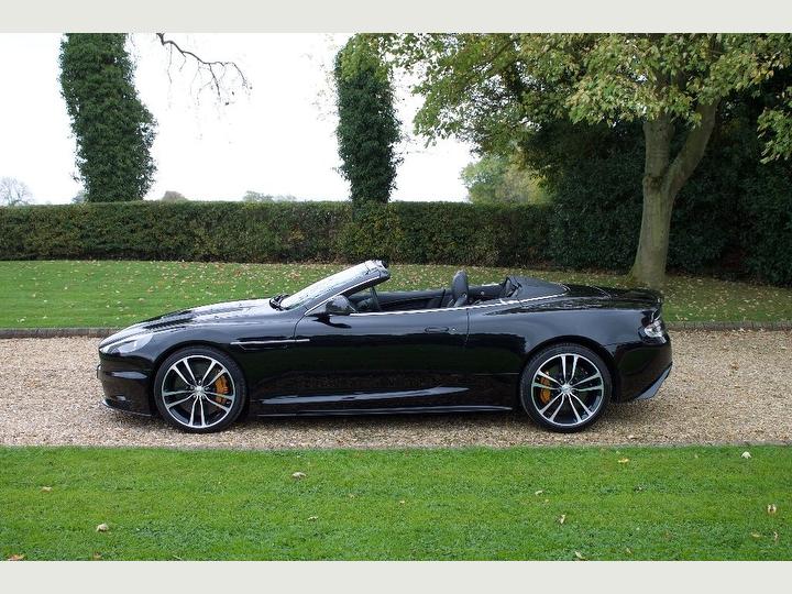 Side profile of a sleek Aston Martin DBS available for hire.